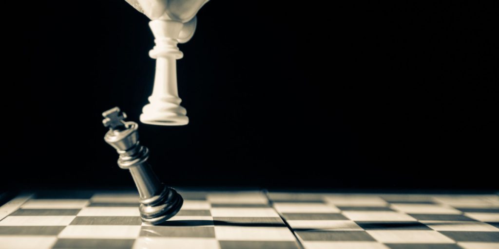 person knocking over chess piece on chess board